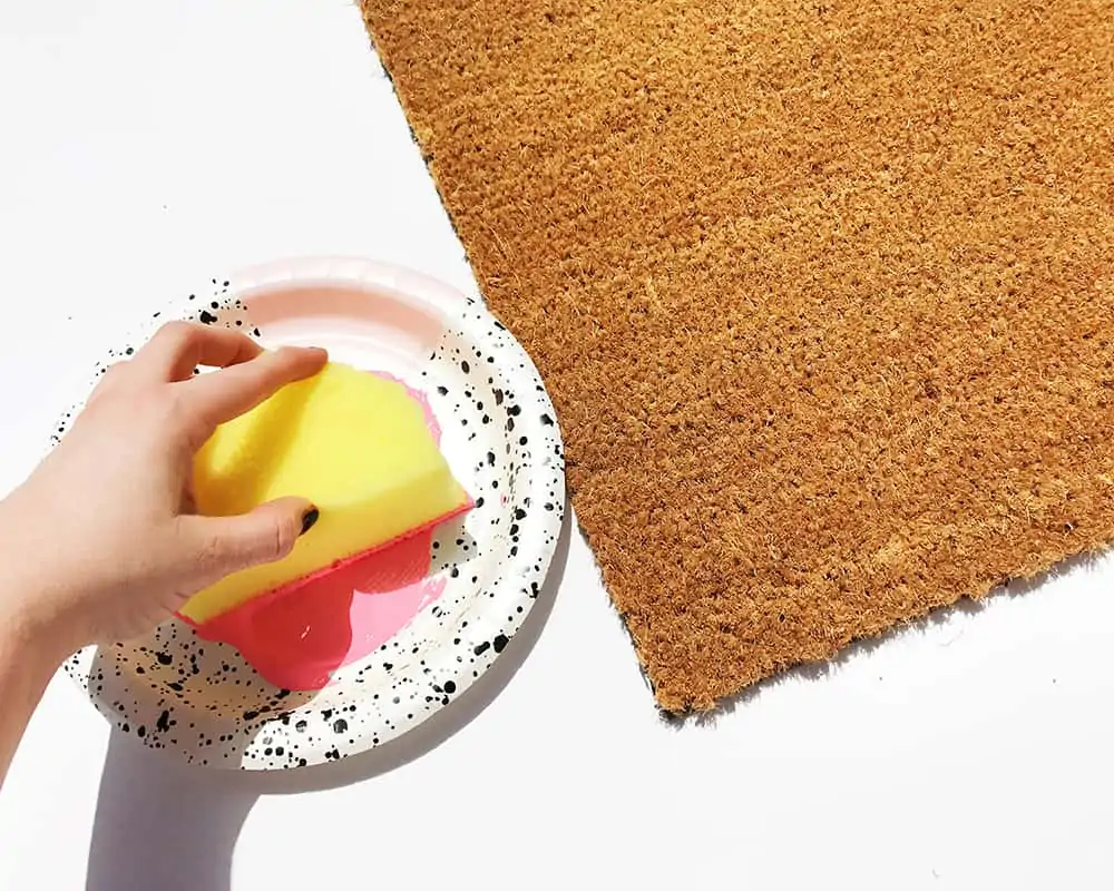 Apply paint to doormat with sponge