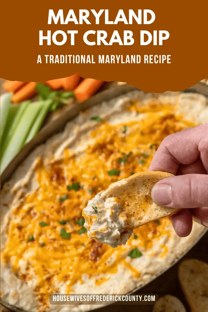 Pinterest pin image for a traditional Maryland hot crab dip recipe, featuring creamy, cheesy crab dip topped with melted cheddar and Old Bay seasoning, with a toasted baguette slice scooping up the dip.
