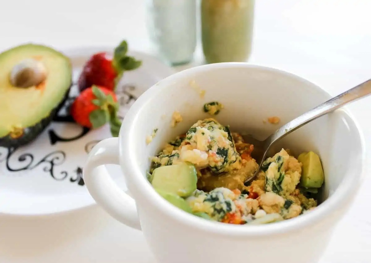 Scrambled eggs in a mug with a side of strawberries