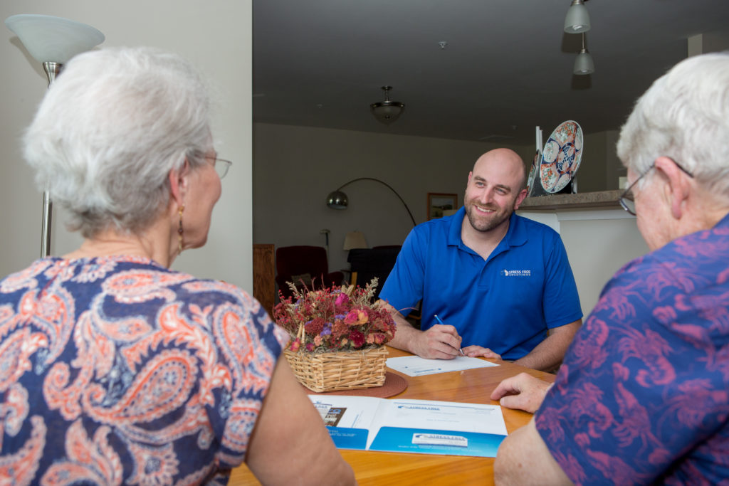 Stress Free Solutions Owner, Ryan Burns, sitting at a table with an older couple explaining his services