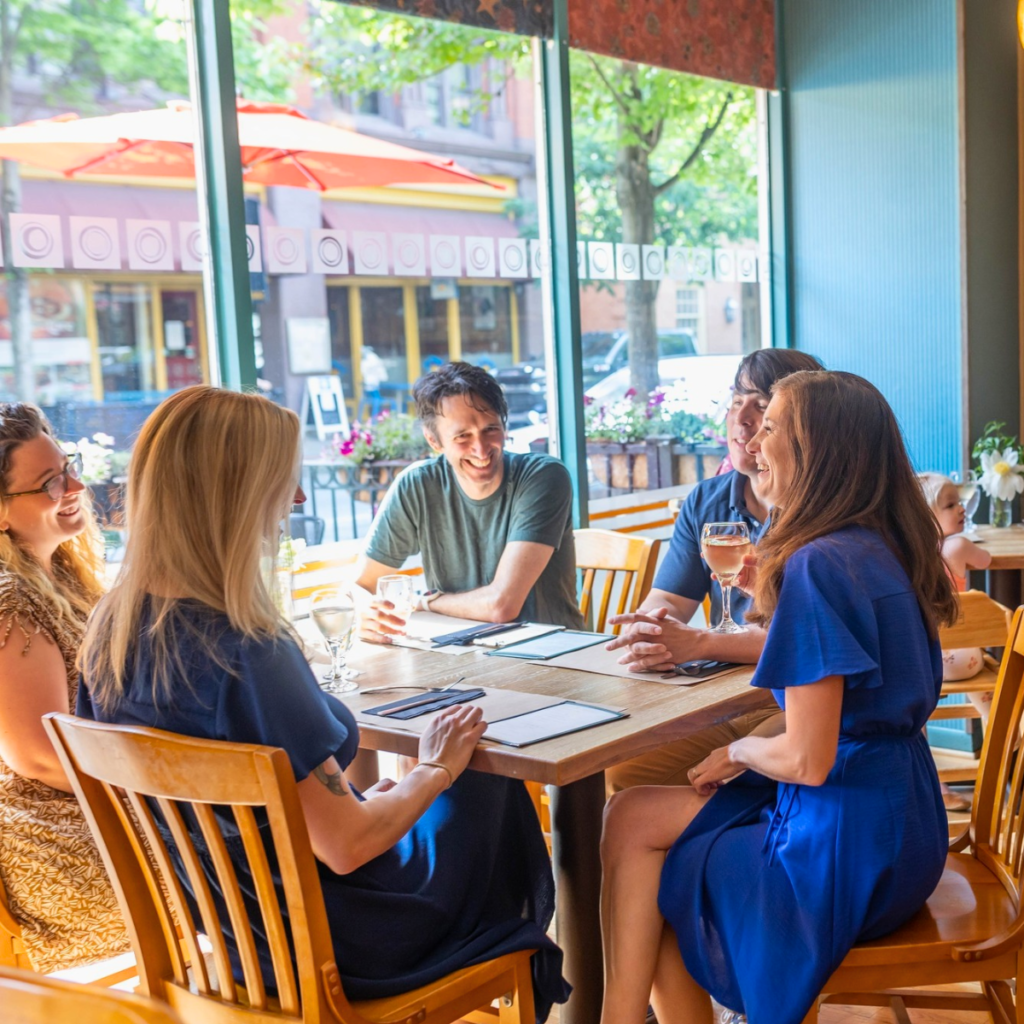Adults sitting at a window seat table drinking drinks and enjoying each other's company at The Orchard Restaurant