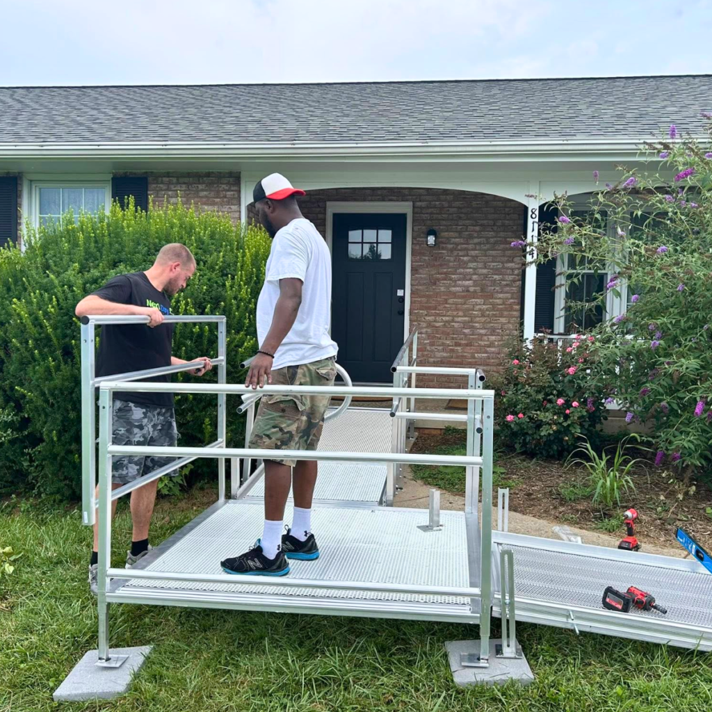 Technicians installing a modular aluminum wheelchair ramp outside a home to improve mobility and accessibility