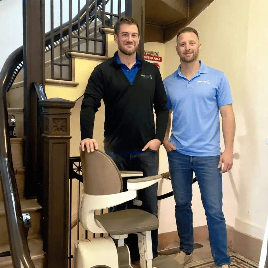 Next Day Access Central Maryland owners standing beside a custom stair lift installed on a historic staircase in Frederick Maryland