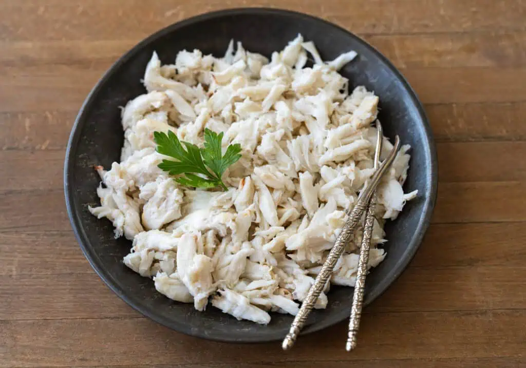 Fresh lump crab meat in a dark bowl with seafood picks