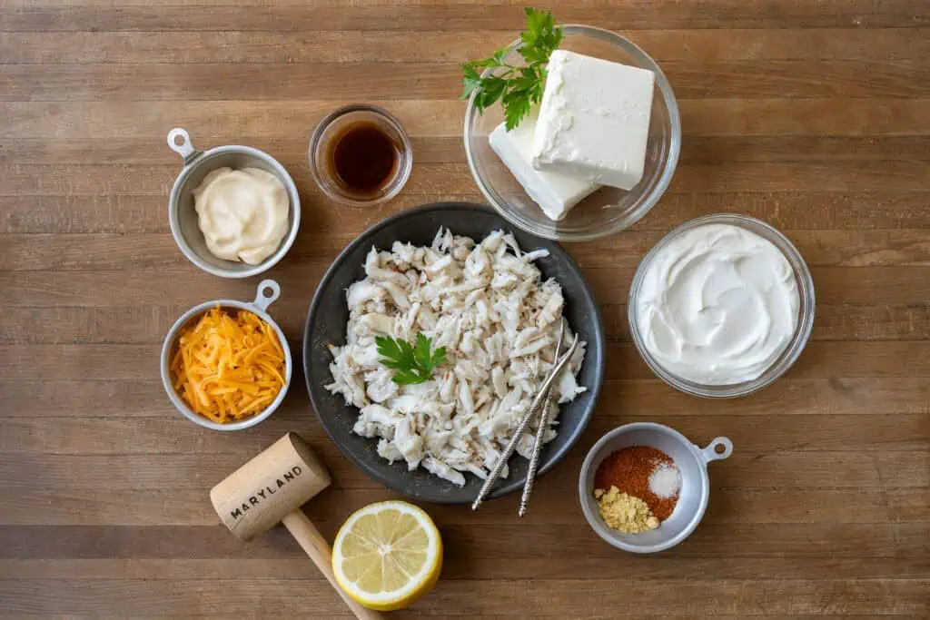 Ingredients for Maryland hot crab dip including crab meat, cream cheese, sour cream, cheddar cheese, lemon and seasonings