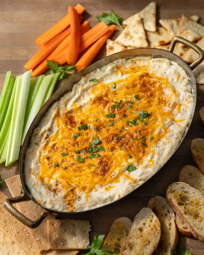 Homemade Maryland hot crab dip topped with melted cheddar cheese and Old Bay seasoning, served with crackers and toasted baguette slices