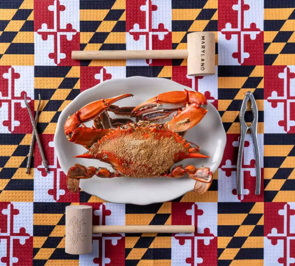 Steamed Maryland blue crab seasoned with Old Bay on a Maryland flag tablecloth with crab mallets